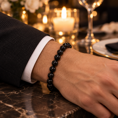 Bransoletka z czarnego onyksu 8 mm na nadgarstku mężczyzny w eleganckiej restauracji przy świecach