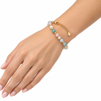 Kolorowa bransoletka z kamieni naturalnych założona na nadgarstek modelki, białe tło
