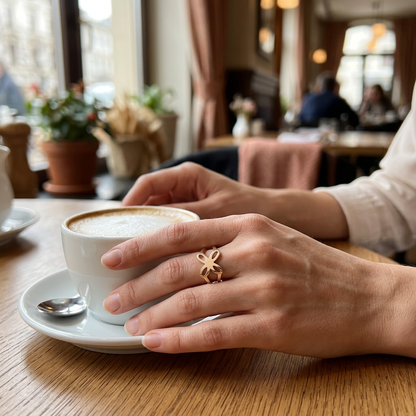 Jeden złoty pierścionek z ażurowym motylem na dłoni przy kawie w restauracji